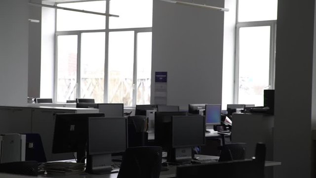 Tracking shot of empty open space office with modern and comfortable workplaces. There are desks with laptop, tablet, computers and stationery on them