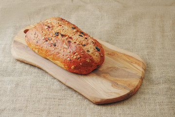 Fresh sourdough loaf bread with cranberry and sunflower seeds on a wooden board and hessian table cloth. Bakery product.