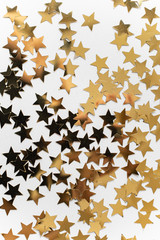 Greeting card with sequins for the inscription, gold spangles in the shape of stars, top view, white background, copy space, flat lay