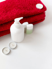 Obraz na płótnie Canvas Disinfectant container, white background, soap dish, for hygiene and cosmetics, minimalism, small jars for shampoo and shower gel, candles, red bath towel for the body, hotel bath set
