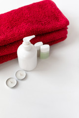 Obraz na płótnie Canvas Disinfectant container, white background, soap dish, for hygiene and cosmetics, minimalism, small jars for shampoo and shower gel, candles, red bath towel for the body, hotel bath set