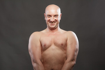 A man with a naked torso shows muscles in the background