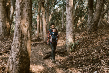 father carrying his baby daughter on a hike in coastal woods