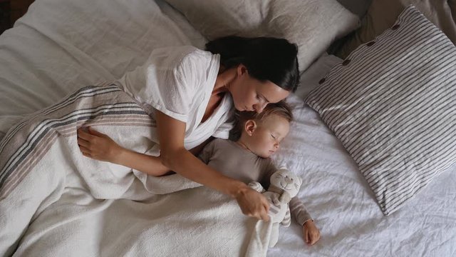 Mother and daughter sleeping on bed in bedroom at home.