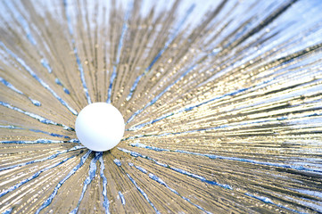 A white table tennis ball pushes through a metallic gold surface, symbolizing speed and power.