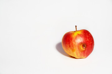 Apple on a white background. Ugly food. The spoiled side of the apple began to rot. Food without GMOs.
