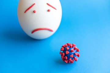 Plasticine model of coronavirus and egg isolate on a blue background. Plasticine model of...