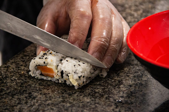 M&atilde;os cortando sushi em close