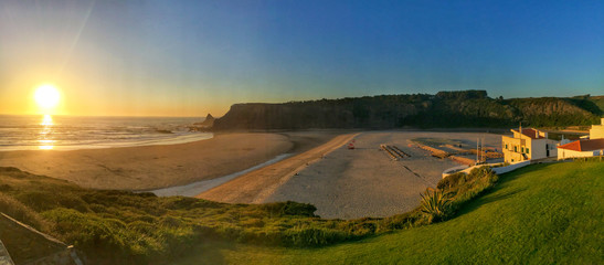 Panoramic view from the cliffs to surfer beach Praia de Odeceixe in the evening sun, District...
