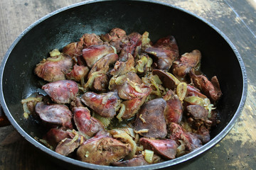 Fried livers with onions in a black pan