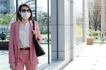 Girl, a young business woman in a protective sterile medical mask on her face in a city. Air pollution, virus, Chinese pandemic coronavirus covid-19 concept.