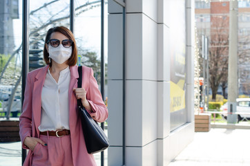 Girl, a young business woman in a protective sterile medical mask on her face in a city. Air pollution, virus, Chinese pandemic coronavirus covid-19 concept.