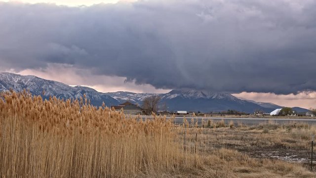 Dark storm clouds rolling over the landscape viewing snow covered mountains.