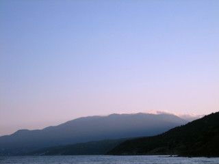 Fototapeta na wymiar Rocky coast at sunset. In the distance, the coast mountains loomed in the mist.