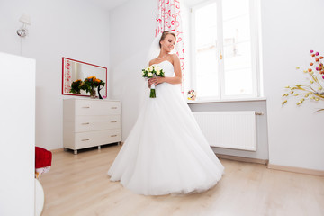 Beautiful bride stands by the window, wedding day