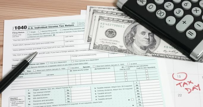 Calculating for US 1040 tax day return form with 100 usd dollar bills and calendar.