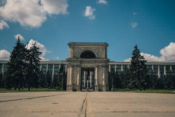 Obraz premium The Triumphal Arch in front of the Government building in Chisinau, Moldova on a warm summer day. Frog view photo