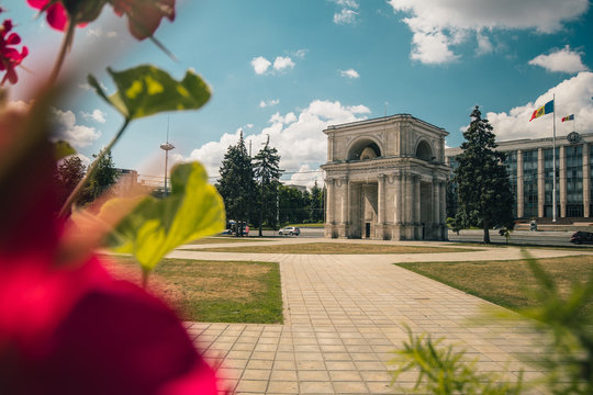 The Triumphal Arch in front of the Government building in Chisinau, Moldova on a warm summer day. Flowers of the park in foreground.