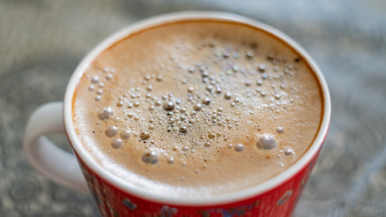 cup of coffee with bubbles on the surface fragment blurred background