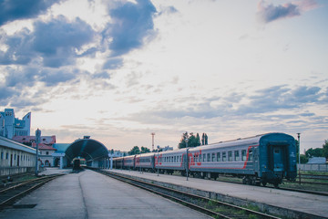 Passenger side of train station in Chisinau, Moldova on a summer evening. Two trains are waiting at the platforms to recieve passengers and tourists.