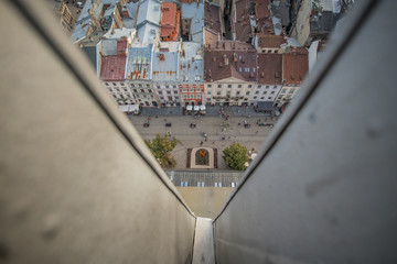 Bird view from the top of the city hall tower in Lviv, Ukraine, looking down to the town square and houses around. Visible people and coat of arms made of flowers.