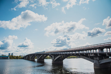 Metro train in Kiev is running over the bridge over Dnieper river towards Hydropark and Dnipro district on a warm summer day in Ukraine.