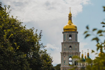 Fototapeta na wymiar Bell tower of Sant Sophia cathedral in Kiev, Ukraine, viewed from distance through the bushes on a sunny day in summer