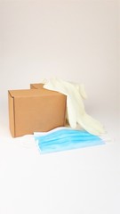 Brown cardboard box,latex white medical gloves and blue medical mask on a white background,copy spaes.Safe delivery of online orders during the coronavirus epidemic,COVID-19,2019-nCoV.