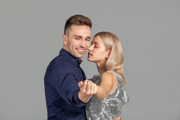 Happy dancing young couple on grey background