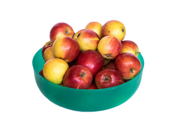 Small ripe yellow and red apples in a green plastic bowl on a white background