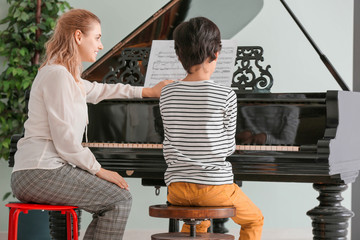 Private music teacher giving piano lessons to little boy