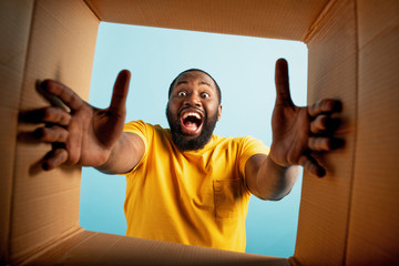 Happy boy receives a package from online shop order. happy and surprised expression. Blue background