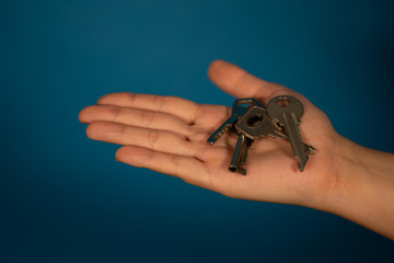 Close-up of hand with different keys. Huddle of keys on woman's palm on blue background.