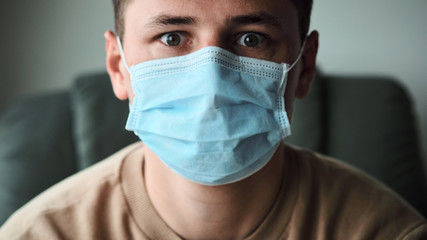 Close-up portrait of young man wearing medical mask and looking at the camera.