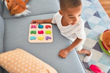 Adorable african american toddler learning maths using mathematics game around lots of toys at...