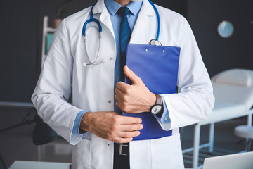 Senior male doctor with clipboard in clinic, closeup