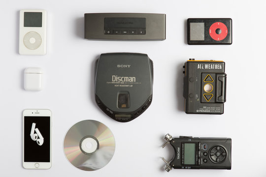 Milan, Italy - March 30, 2020: flat lay on white background with miscellaneous technology objects and music listening devices from all ages.