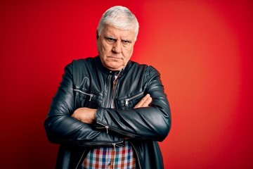 Senior handsome hoary man wearing casual shirt and jacket over isolated red background skeptic and...