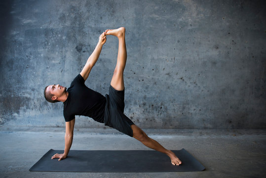 Man practicing yoga, advanced version of sideplank (Vasisthasana in Sanskrit) 