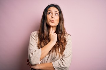 Fototapeta premium Young beautiful brunette woman wearing casual sweater standing over pink background Thinking concentrated about doubt with finger on chin and looking up wondering
