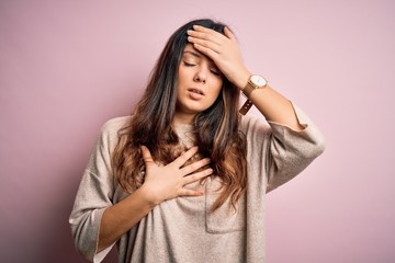 Young beautiful brunette woman wearing casual sweater standing over pink background Touching forehead for illness and fever, flu and cold, virus sick