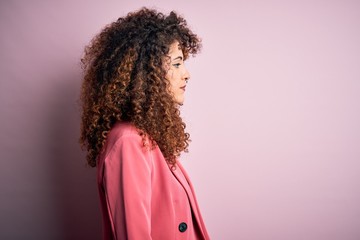 Young beautiful businesswoman with curly hair and piercing wearing elegant jacket looking to side,...