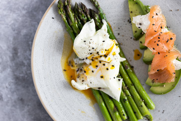 Green asparagus with poached egg, avocado , creme cheese and salmon on a plate
