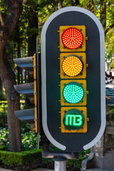 A closeup shot of a traffic light with all the coloured lights on