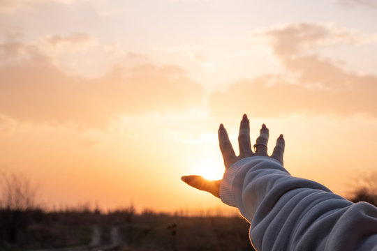 Photo of a female hand reaching amazing sunset, beautiful nature