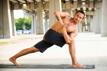 Fototapeta na wymiar Mexican man practicing yoga in a urban background