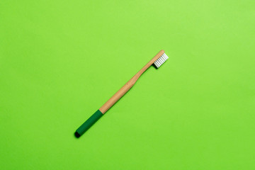 dark green bamboo toothbrush on a green background. eco friendly. isolate