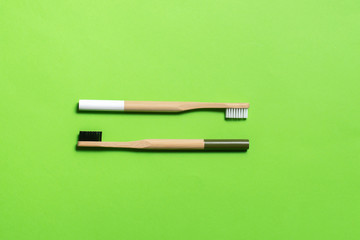 white and dark green bamboo toothbrushes on a green background. eco friendly. isolate