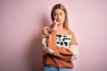 Young beautiful blonde woman wearing fashion animal print sweater over pink background with hand on chin thinking about question, pensive expression. Smiling with thoughtful face. Doubt concept.