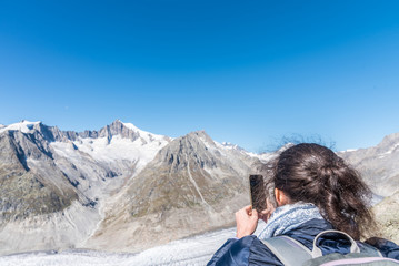 Rear view of woman photographing Aletsch Glacier with smartphone from Eggishorn viewpoint